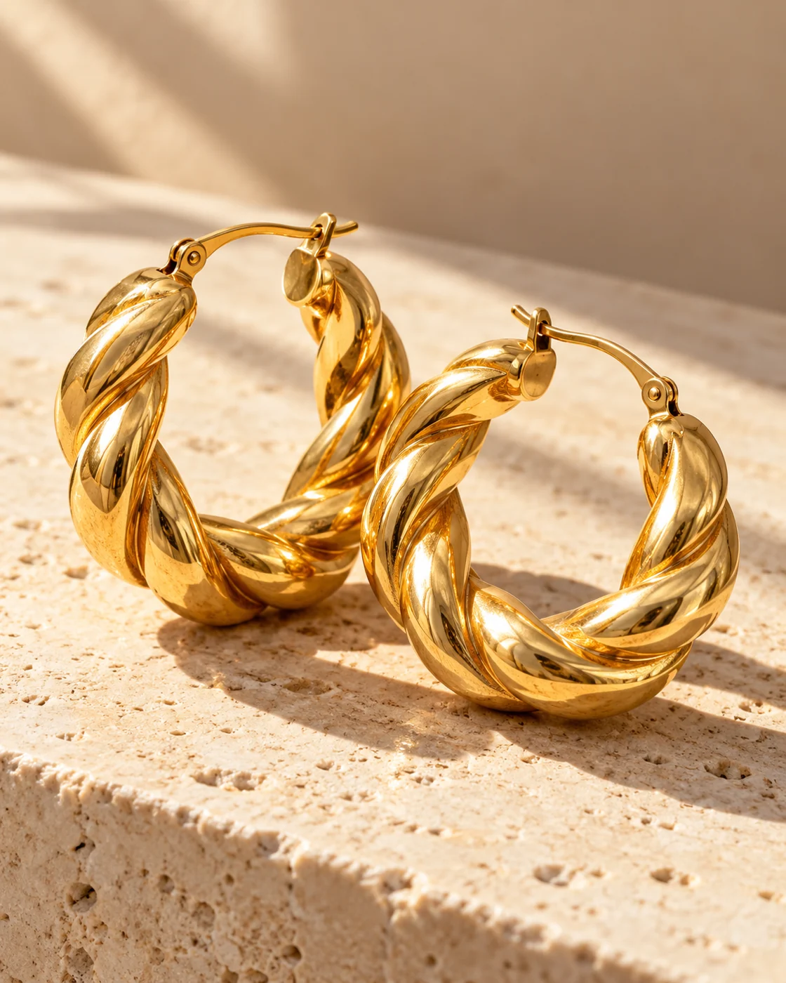 Sculptural gold hoop earrings on ivory stone